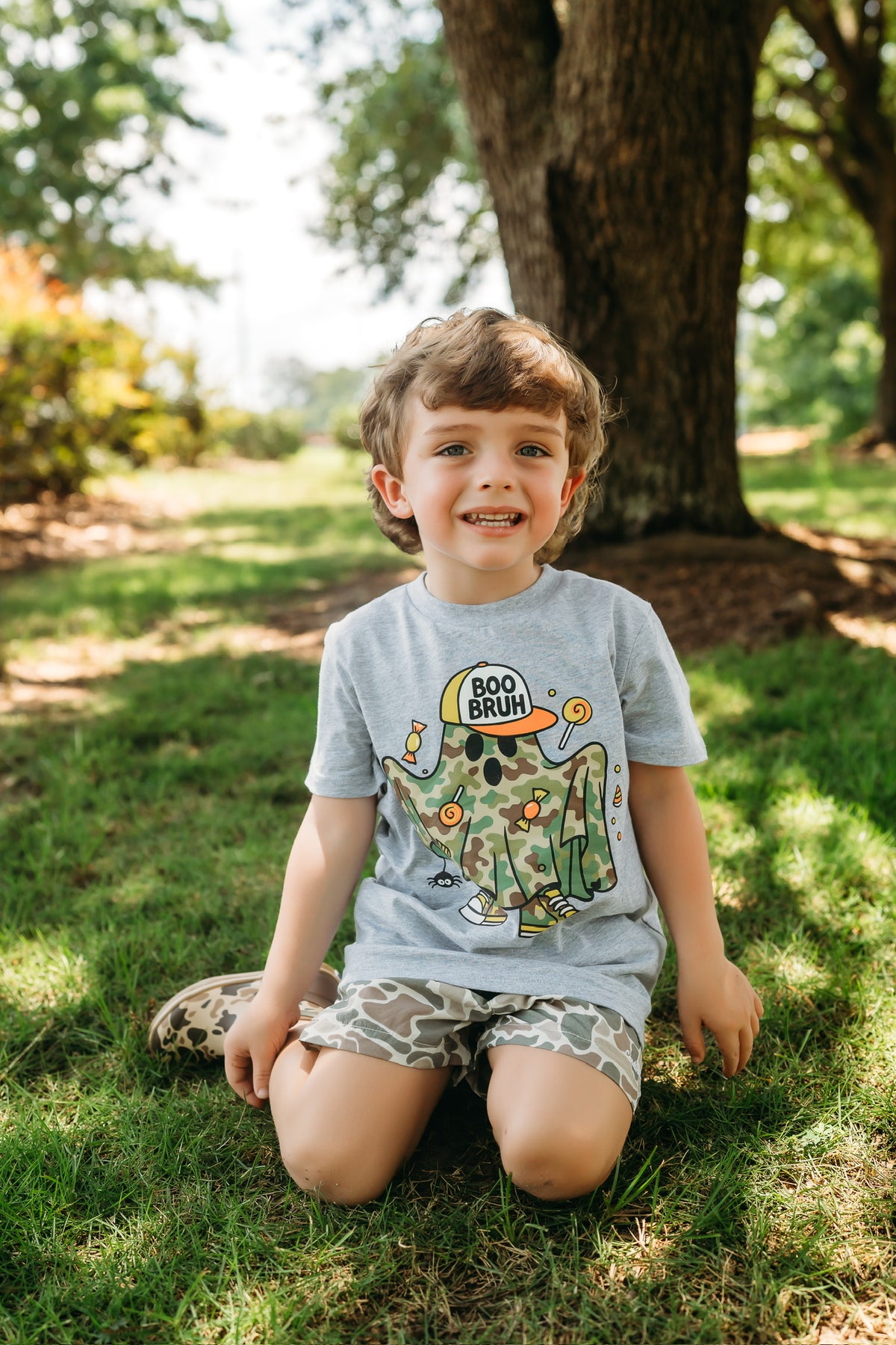 A smiling child outside wearing a gray Cardin McCoy graphic tee.